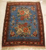 An Ashfar rug, the central panel set with floral sprays on a blue ground, within a stepped red,