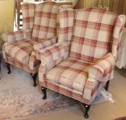 A pair of modern wing back arm chairs raised on cabriole legs with tartan upholstery (possibly