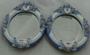 A pair of Continental oval table mirrors in porcelain floral encrusted frames,