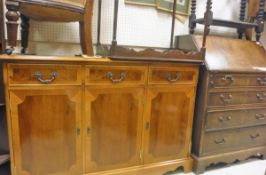 A 20th Century yew sideboard of three drawers above three cupboard doors with a shaped apron,