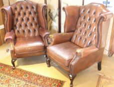 A pair of Georgian style brown leather wing back armchairs with cabriole front legs