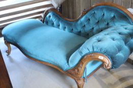 A Victorian walnut framed chaise longue with button back and shaped front with carved detail raised