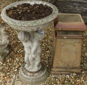 A composite stone garden bird bath / planter, the dished top supported by a pedestal as three putti,
