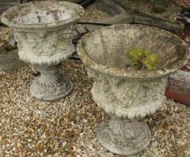 A pair of composite stone garden urns, each with floral swag and lion mask decoration,