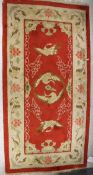 A Chinese silk rug, the central panel set with cranes on a red ground,