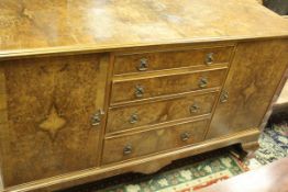 A 20th Century burr walnut veneered sideboard with four central drawers flanked by two cupboard