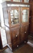 An Indian teak food cupboard with a pair of mirrored cupboard doors above two further cupboard