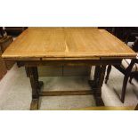 An oak extending dining table on twin columnar end supports and a stretchered base