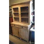 A pine dresser with two glazed doors enclosing shelves above two drawers and two cupboard doors to