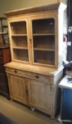A pine dresser with two glazed doors enclosing shelves above two drawers and two cupboard doors to