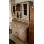 A pine dresser with various open recesses and glazed doors and drawers above a base of two drawers