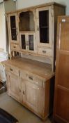 A pine dresser with various open recesses and glazed doors and drawers above a base of two drawers