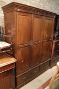 A late Victorian stained beech triple wardrobe with hanging space and linen drawers over two