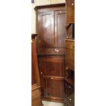 An early 19th Century oak hanging corner cupboard of two doors over two drawers,