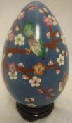 A large Chinese cloisonné egg decorated with flowers onto a blue ground