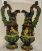 A pair of Majolica ewers by Robert Hanke with scrolling foliate handles topped by maiden masks,