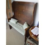 A circa 1900 oak wing back tavern settle of panelled form on plank end supports