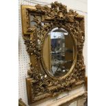 An oval bevelled mirror with carved gilt floral and foliate frame,