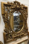 An oval bevelled mirror with carved gilt floral and foliate frame,