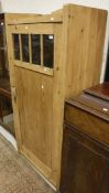 A pine single door cupboard with glass top section,