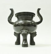 A 19th Century Chinese bronze censer with two S shaped handles emanating from the body,