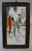 A Chinese polychrome decorated porcelain tile depicting two figures in a landscape with script,