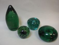 Three Victorian green glass dumps as doorstops and one as a paperweight with blue swirl and bubble
