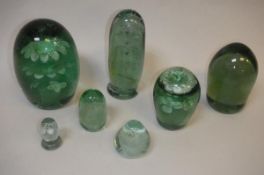 Seven Victorian green glass dump paperweights with internal decoration,