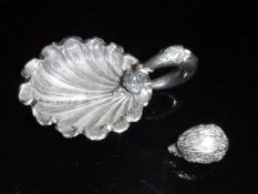 A Victorian silver caddy spoon in the form of a shell with grape and vine decorated loop handle (by