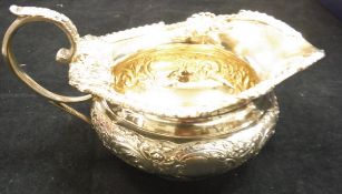 A late Victorian silver jug of squat form with heavy mask and acanthus applied decoration and gilt
