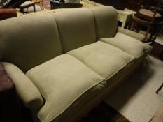 A modern pale green upholstered three seat scroll arm sofa with tassled base in the Howard style