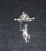 A silver and paste mounted brooch, modelled as a monkey seated on a bar,