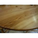 A modern pitch pine circular dining table on centre pedestal to tripod base