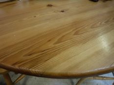 A modern pitch pine circular dining table on centre pedestal to tripod base