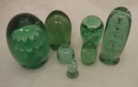 Seven Victorian green glass dump paperweights with internal decoration,