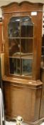 A corner display cabinet with astragal glazed door above a cupboard door,