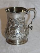 A George II silver baluster shaped mug with later embossed foliate and scrolling decoration (by