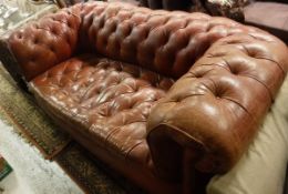 A circa 1900 buttoned red leather upholstered Chesterfield sofa on turned and ringed front legs to