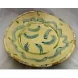 A studio pottery charger with blue and green trailing decoration on a cream ground,