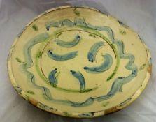 A studio pottery charger with blue and green trailing decoration on a cream ground,