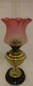 A Victorian brass oil lamp with etched cranberry glass shade and clear glass funnel