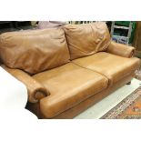 A modern brown leather three seat sofa raised on ringed and turned bun feet