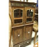 An Indian teak food cupboard with a pair of mirrored cupboard doors above two further cupboard