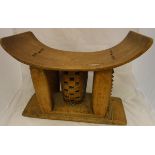 An Ashanti tribal carved wooden stool raised on five carved pillar supports to central rectangular