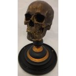 A modern ornament in the form of a skull raised upon a turned stand,