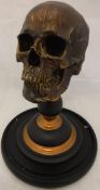 A modern ornament in the form of a skull raised upon a turned stand,