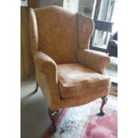 A 19th Century wing back arm chair raised on swept front legs,