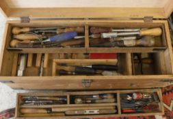 A wooden toolbox containing various hand tools to include chisels, level, drill bits etc,