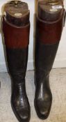 A pair of black and tan hunting boots with wooden trees,