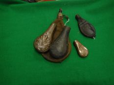 A collection of five various shot/powder flasks, three leather,